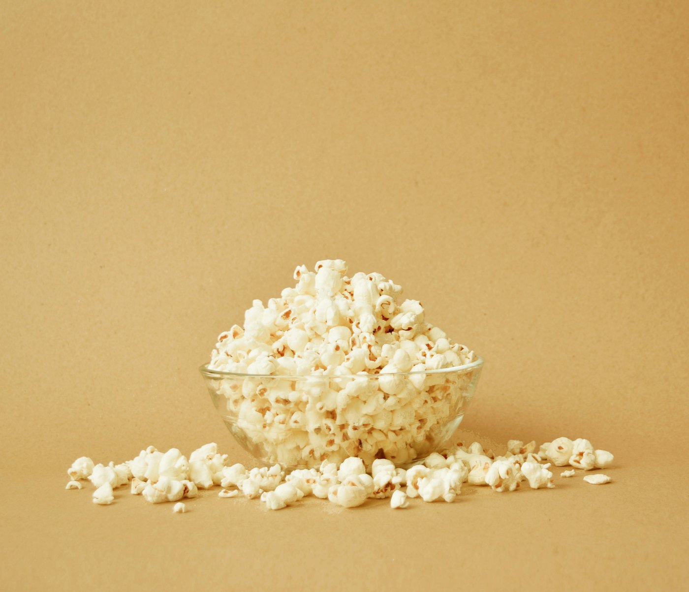 A bowl of popcorn on a warm yellow table
