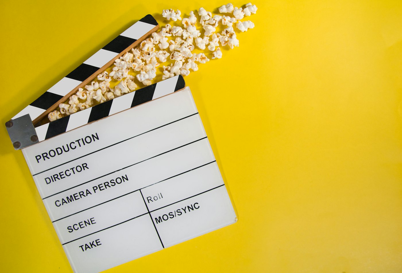 A film clapperboard beside a bowl of popcorn for movie night